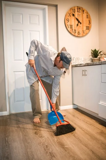 A housekeeper straightening the bed linens in a well-appointed hotel room.